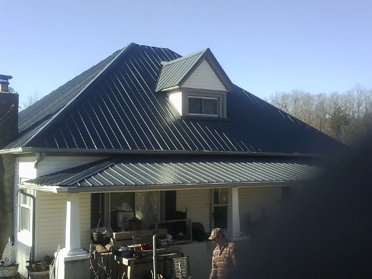 Dark blue standing seam metal roof with a dormer above a front porch in Gerlaw
