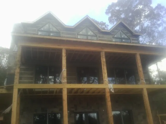 Dormers and porch framing on a large log home under construction — Roof Coating work by our crew in Gerlaw