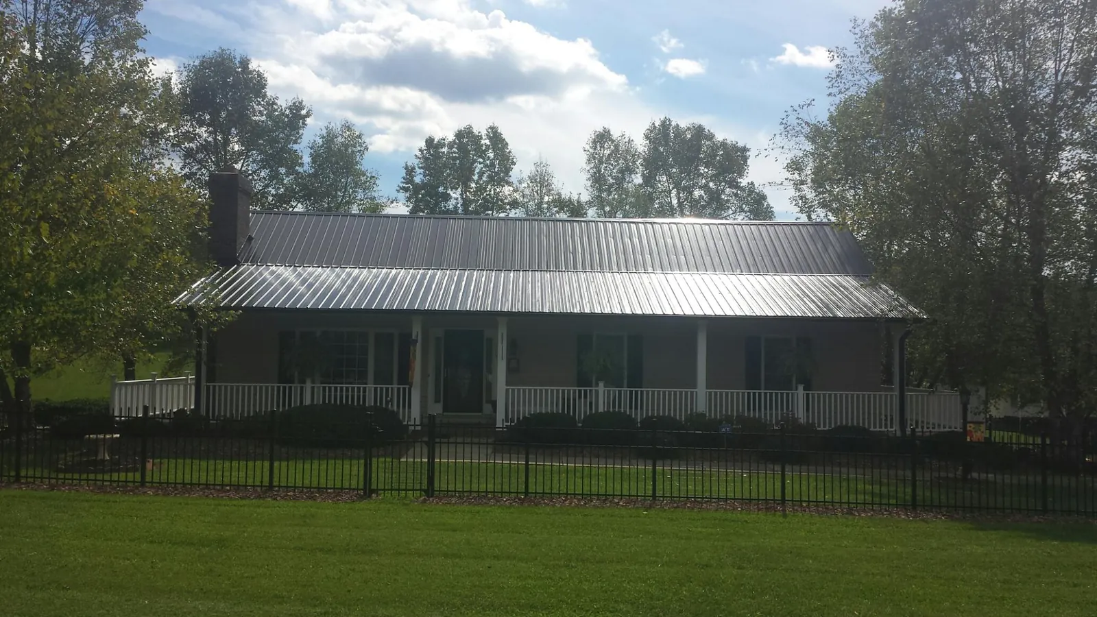 Gray metal roof on a brick ranch with a full width front porch — Gutter Guard Installation work by our crew in Gerlaw