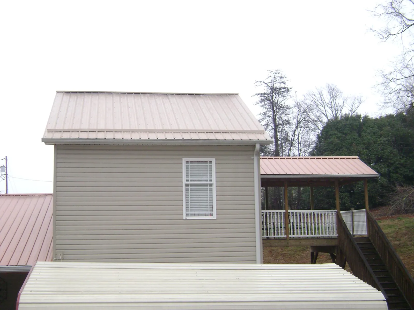 Tan metal roofs on a two story addition and attached porch, from a Roof Replacement job in Gerlaw