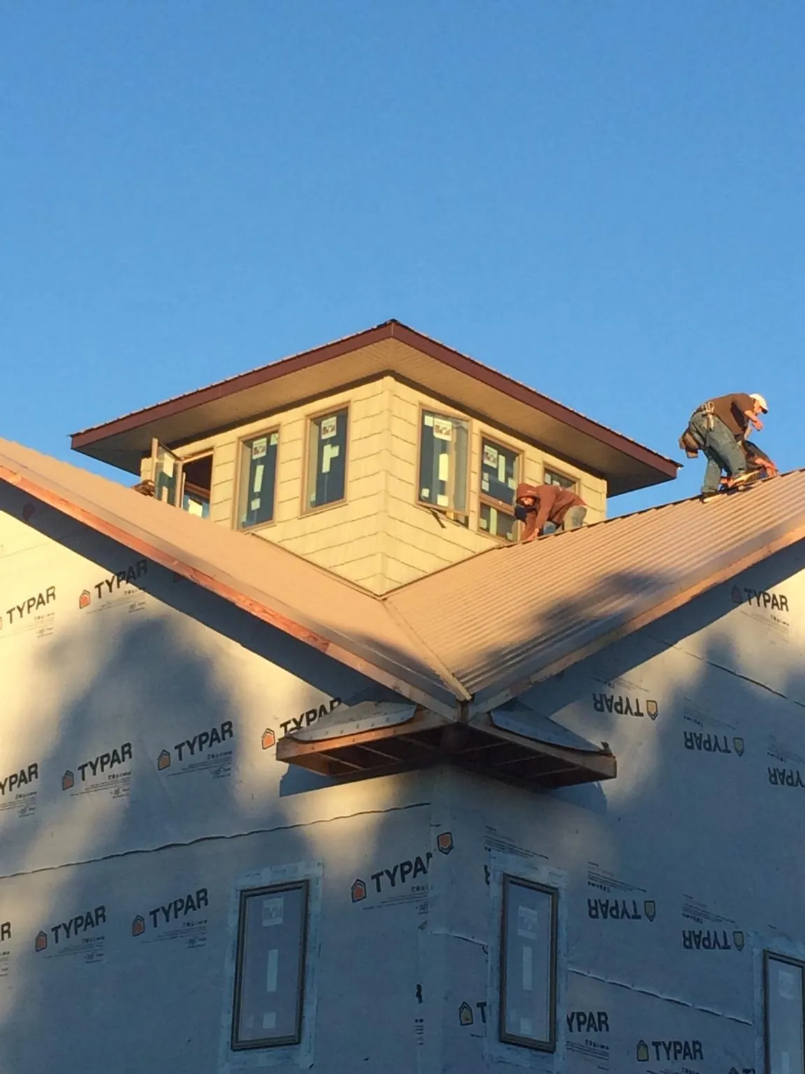 Roofers working around a rooftop cupola on a new metal roof at sunset — Roof Waterproofing in Gerlaw by Roofing Brothers